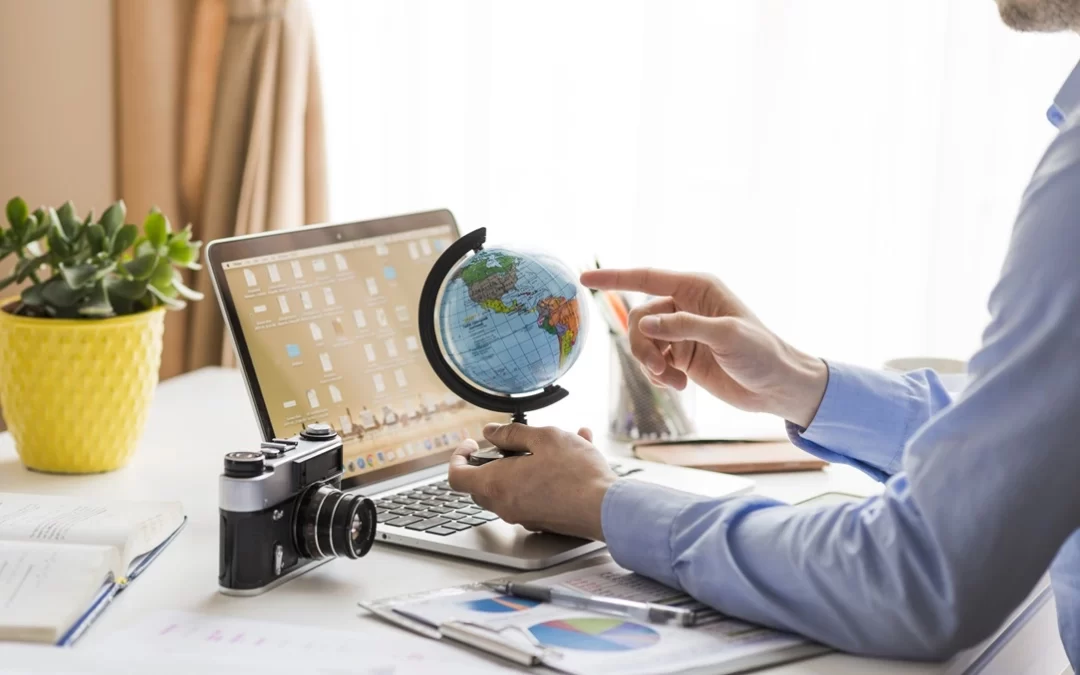 Un hombre de negocios sostiene un mapamundi en formato globo terráqueo con un cuaderno sobre la mesa